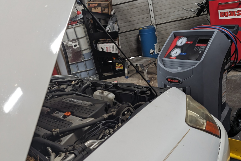 a/c repair, auto repair shop in summerville, SC. SBS Automotive. Image shows a white Honda undergoing air conditioning service with a Robinair A/C machine connected, highlighting summer cooling care.
