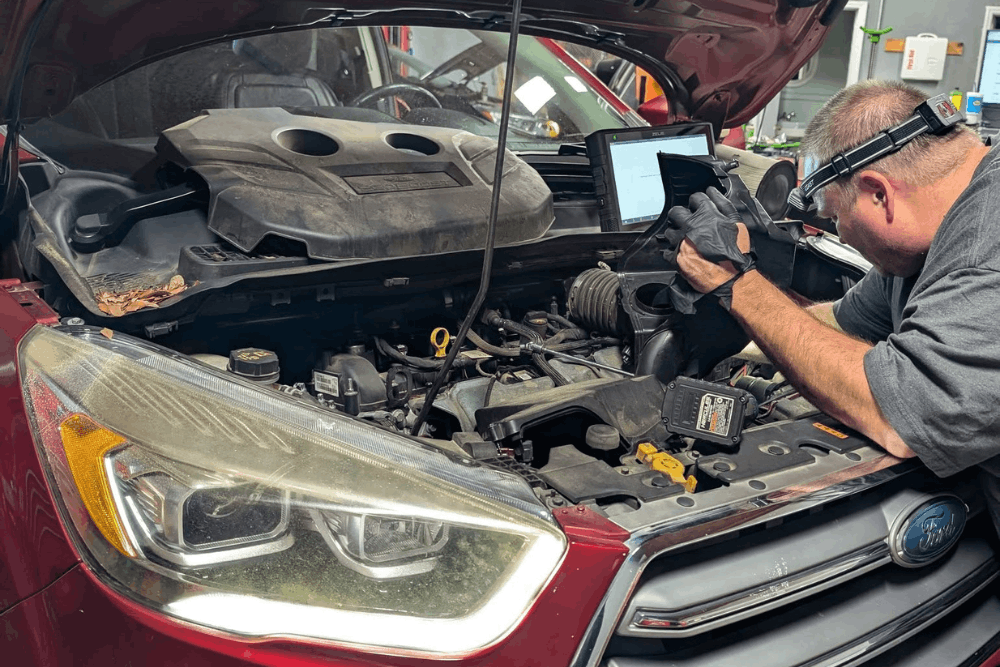 Car Tune-up in Summerville, SC by SBS Automotive Maintenance and Repair. Technician inspecting the intake system under the hood of a red SUV using a professional scan tool.